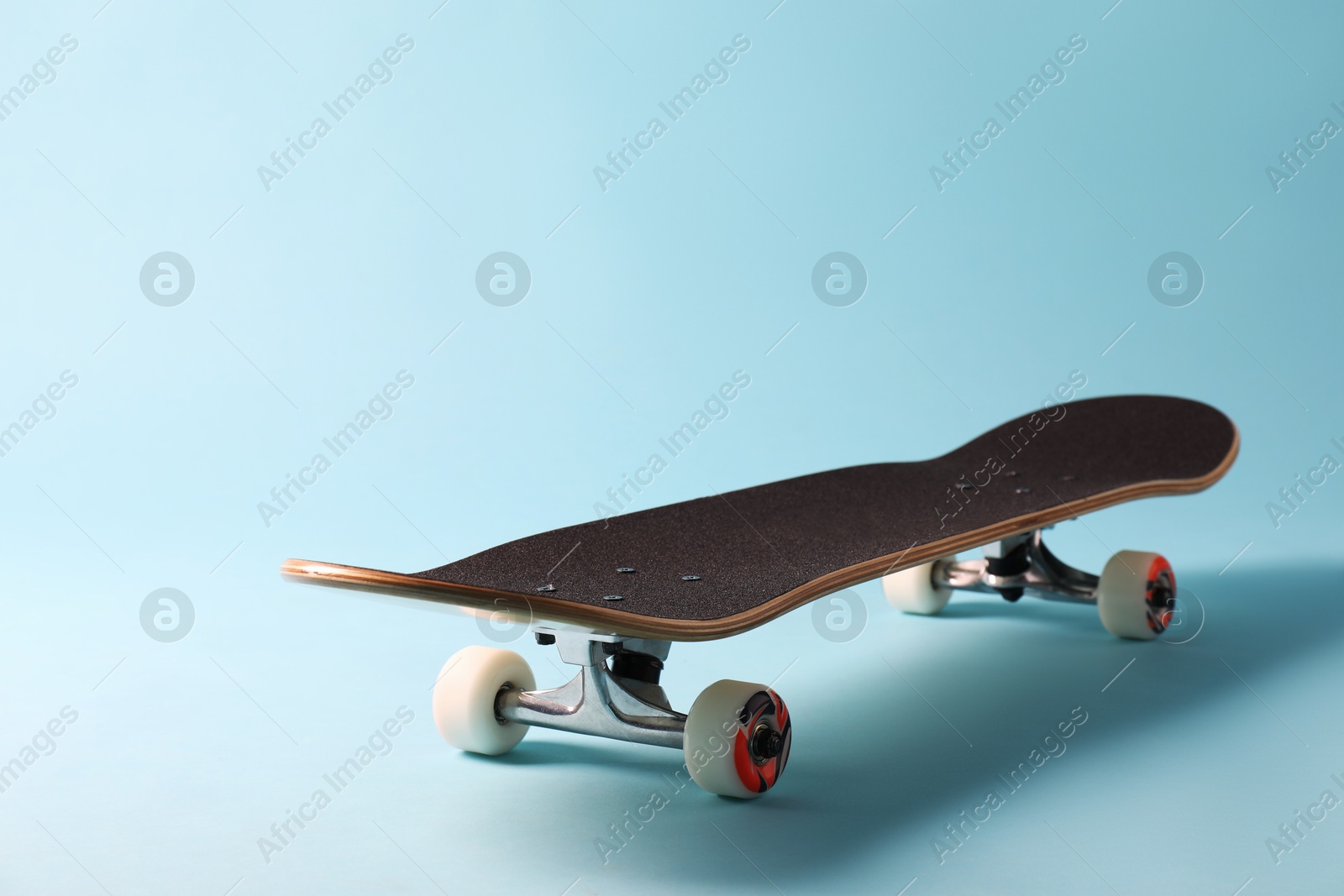 Photo of One skateboard on light blue background, closeup. Sports equipment