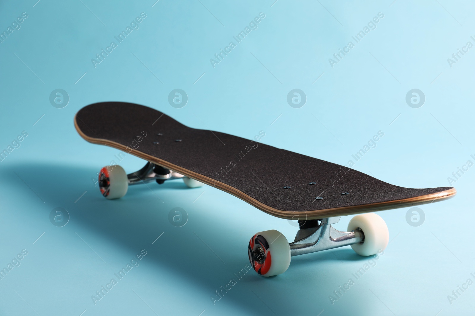 Photo of One skateboard on light blue background, closeup. Sports equipment