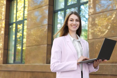 Photo of Portrait of young woman with laptop wearing stylish suit outdoors