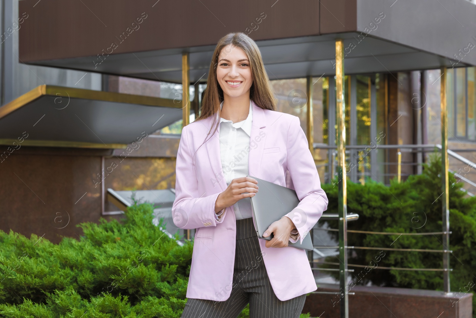 Photo of Portrait of young woman with laptop wearing stylish suit outdoors