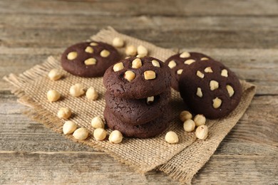 Photo of Tasty chocolate cookies with hazelnuts on wooden table, closeup