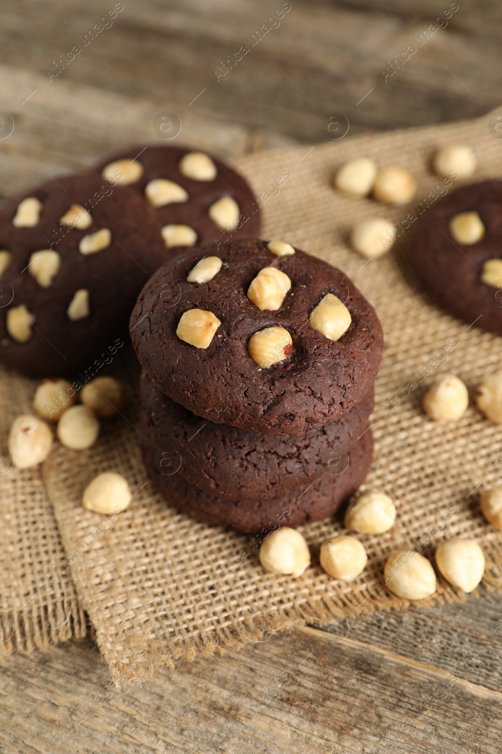 Photo of Tasty chocolate cookies with hazelnuts on wooden table, closeup