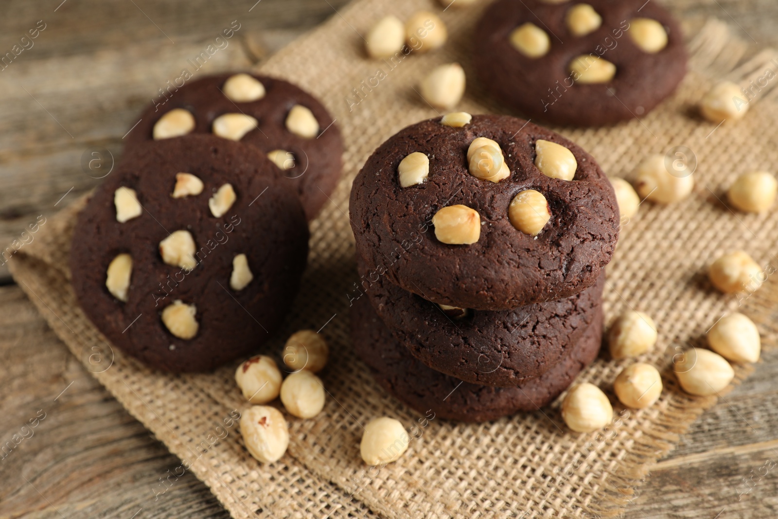 Photo of Tasty chocolate cookies with hazelnuts on wooden table, closeup