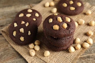 Photo of Tasty chocolate cookies with hazelnuts on wooden table, closeup