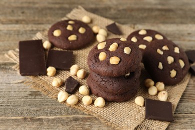 Photo of Tasty chocolate cookies with hazelnuts on wooden table, closeup