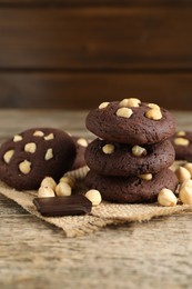 Photo of Tasty chocolate cookies with hazelnuts on wooden table, closeup