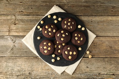 Photo of Tasty chocolate cookies with hazelnuts on wooden table, top view