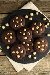 Photo of Tasty chocolate cookies with hazelnuts on wooden table, top view