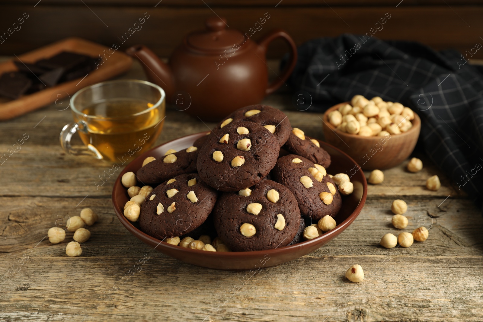 Photo of Tasty chocolate cookies with hazelnuts and tea on wooden table