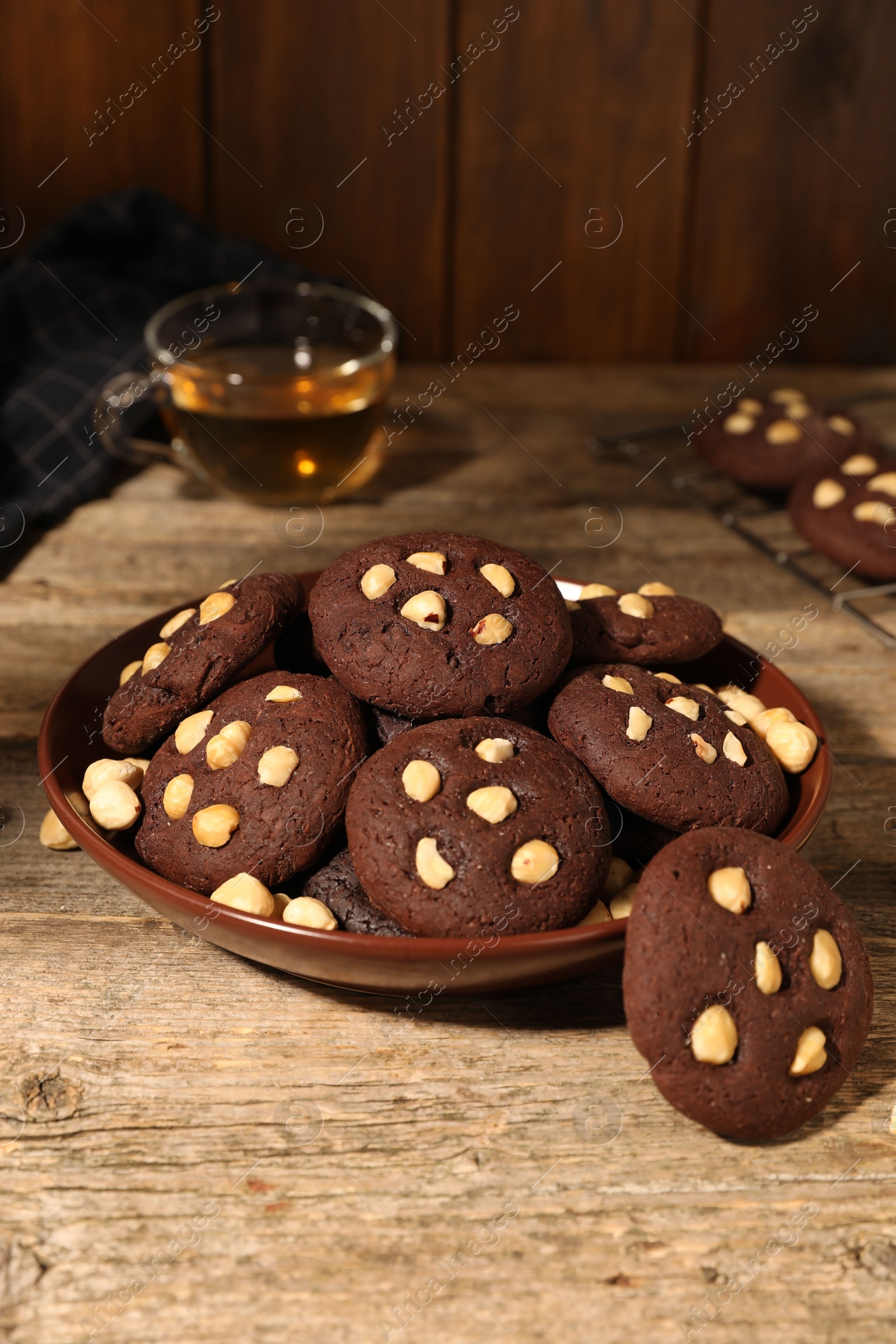 Photo of Tasty chocolate cookies with hazelnuts on wooden table