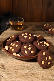 Photo of Tasty chocolate cookies with hazelnuts on wooden table