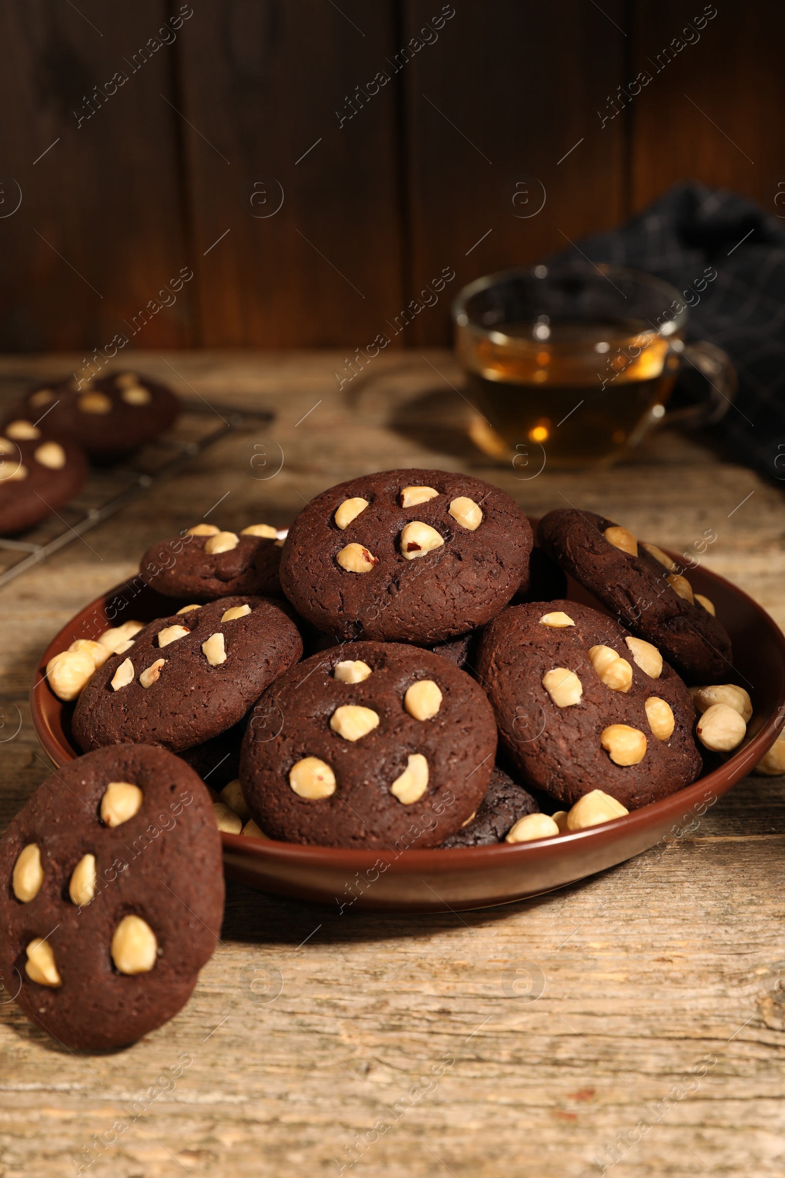 Photo of Tasty chocolate cookies with hazelnuts on wooden table