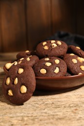 Photo of Tasty chocolate cookies with hazelnuts on wooden table, closeup