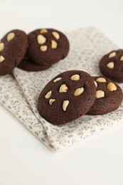 Photo of Tasty chocolate cookies with hazelnuts on white table, closeup