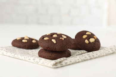 Photo of Tasty chocolate cookies with hazelnuts on white table, closeup