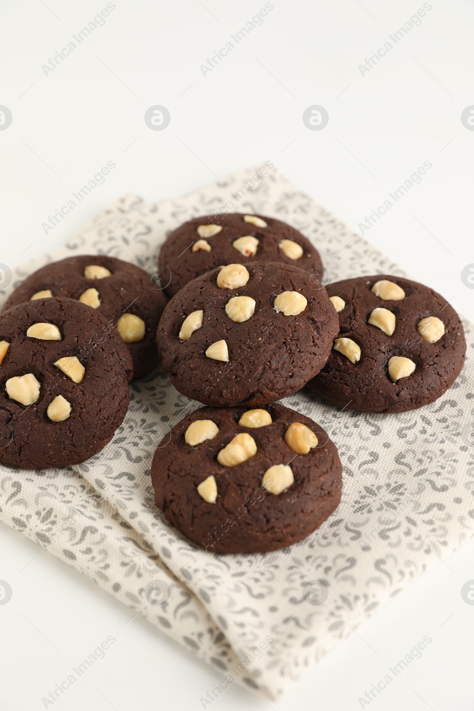 Photo of Tasty chocolate cookies with hazelnuts on white table, closeup