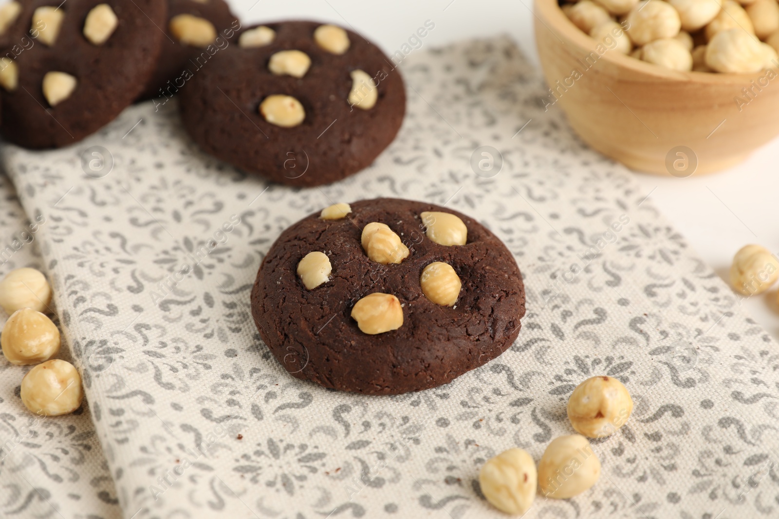 Photo of Tasty chocolate cookies with hazelnuts on table, closeup