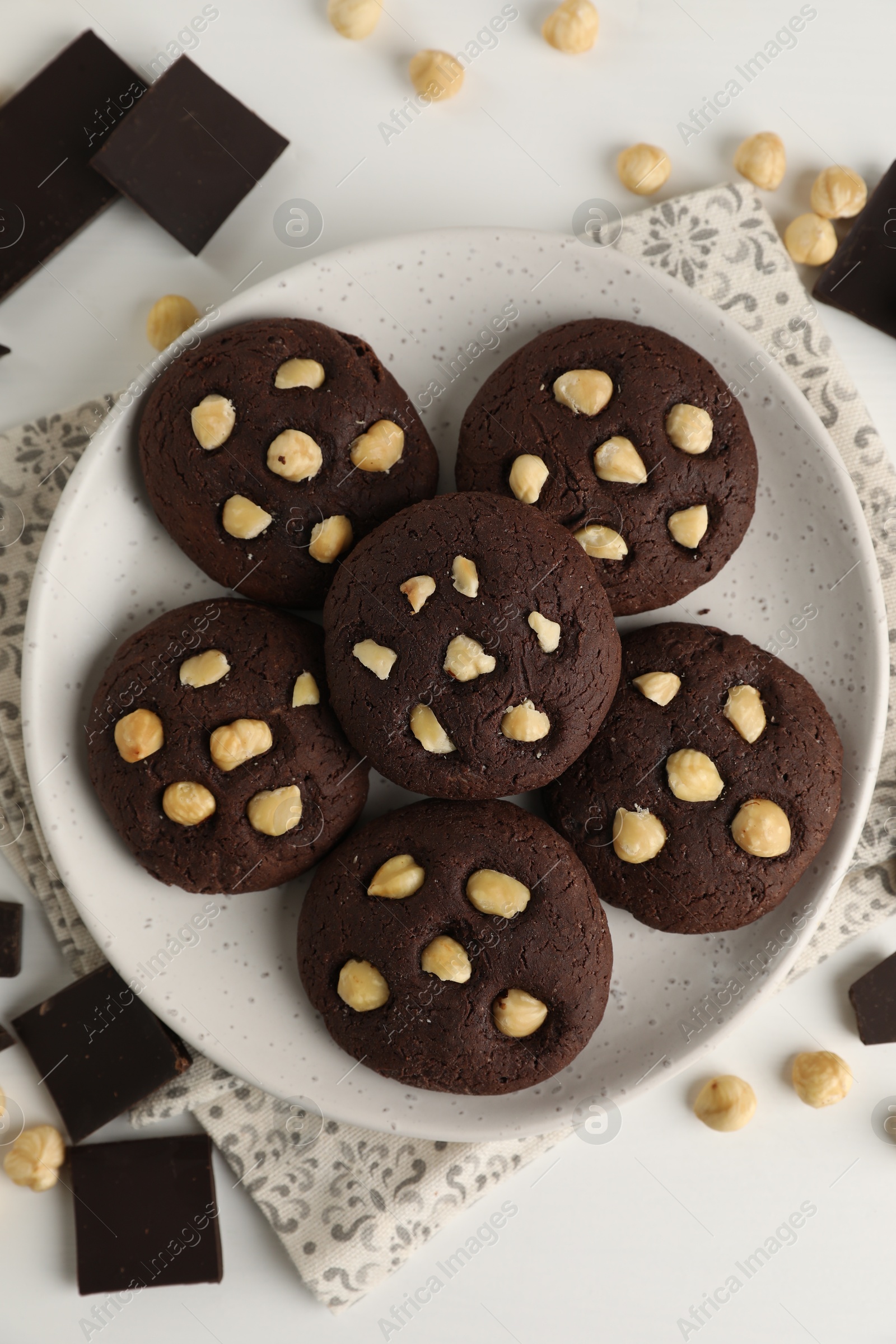 Photo of Tasty chocolate cookies with hazelnuts on white table, flat lay