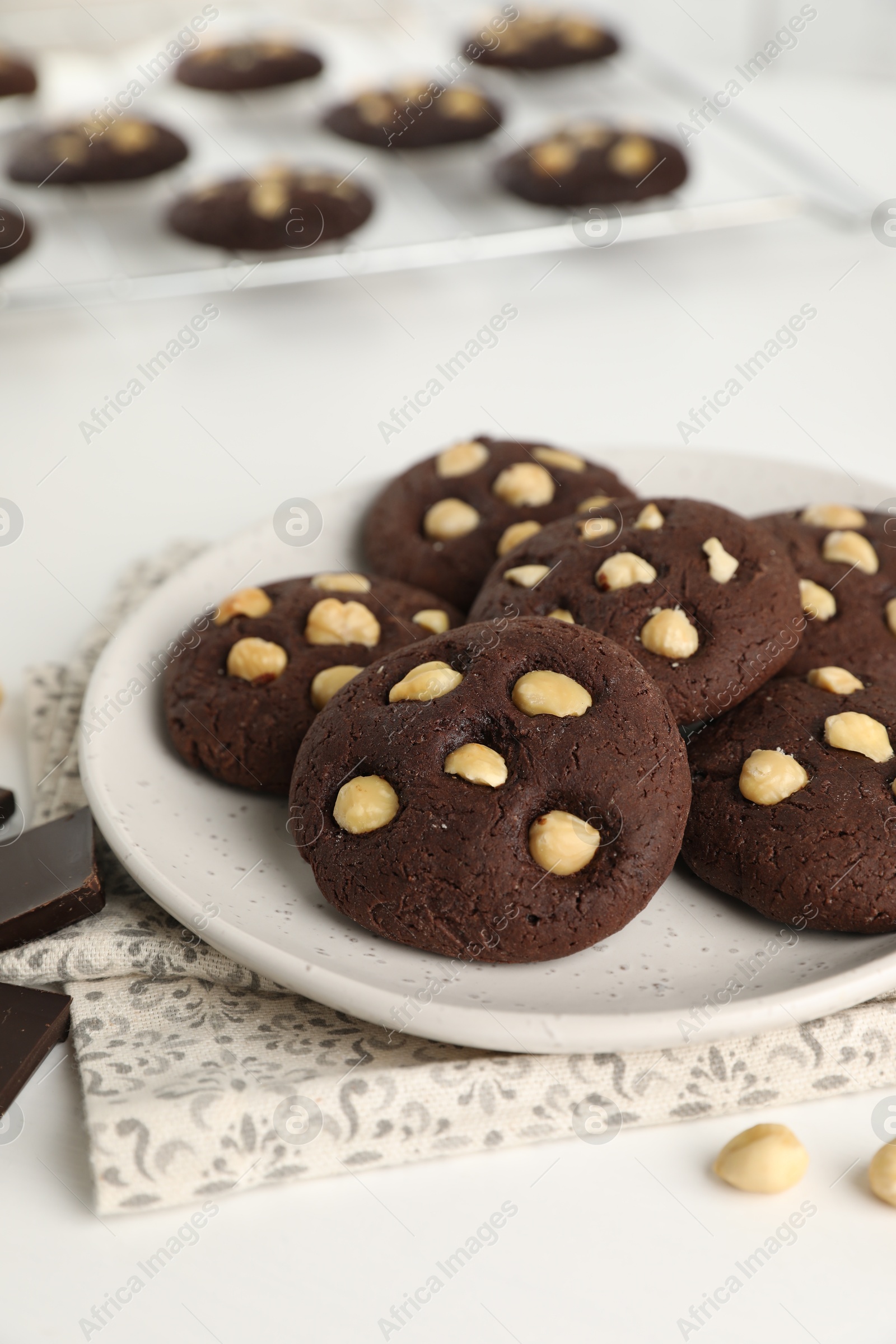 Photo of Tasty chocolate cookies with hazelnuts on white table, closeup