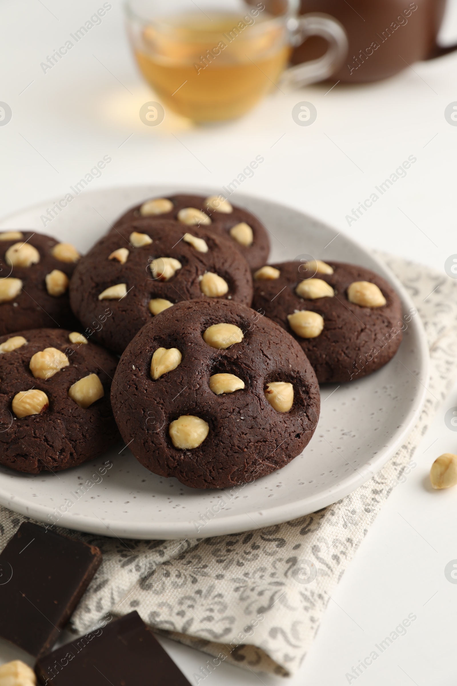 Photo of Tasty chocolate cookies with hazelnuts on white table, closeup