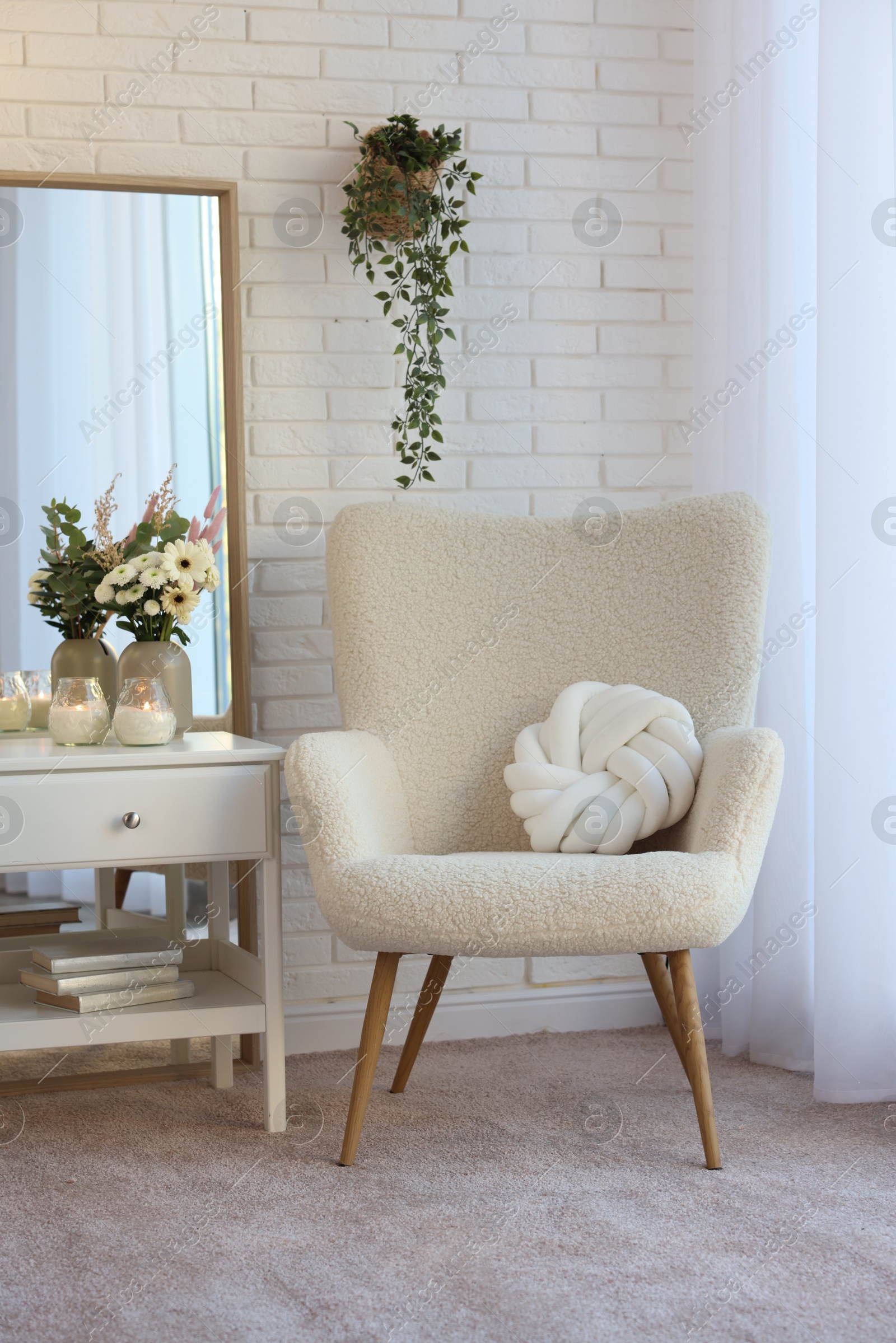 Photo of Soft armchair, side table and mirror in room