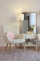 Photo of Soft armchair, side table and mirror in room