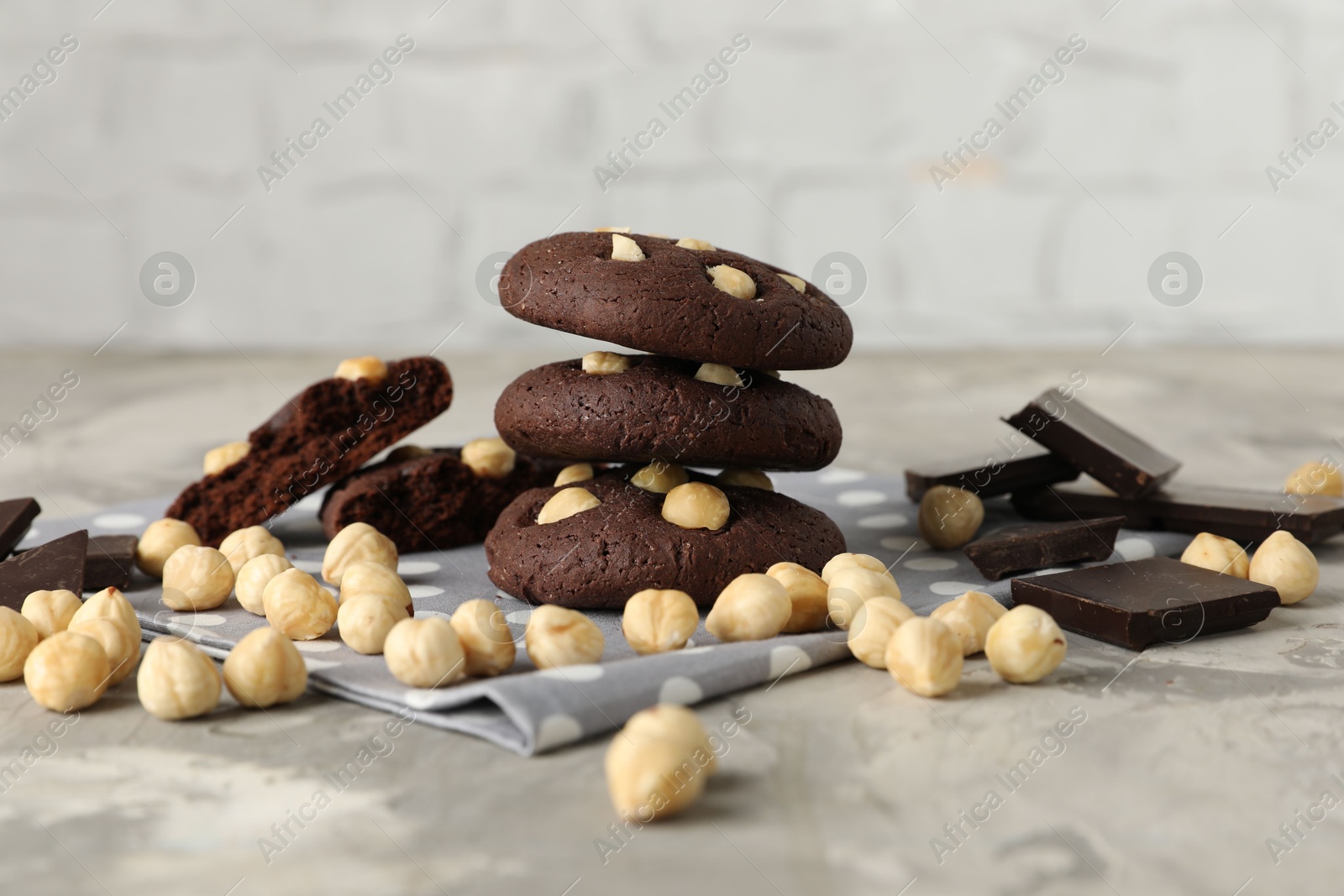 Photo of Tasty chocolate cookies with hazelnuts on grey table, closeup