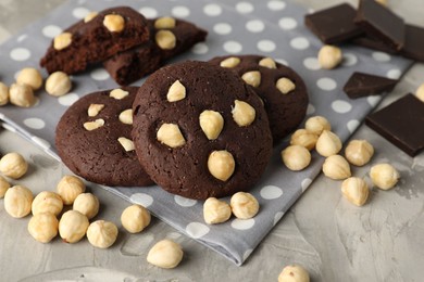 Photo of Tasty chocolate cookies with hazelnuts on grey table, closeup