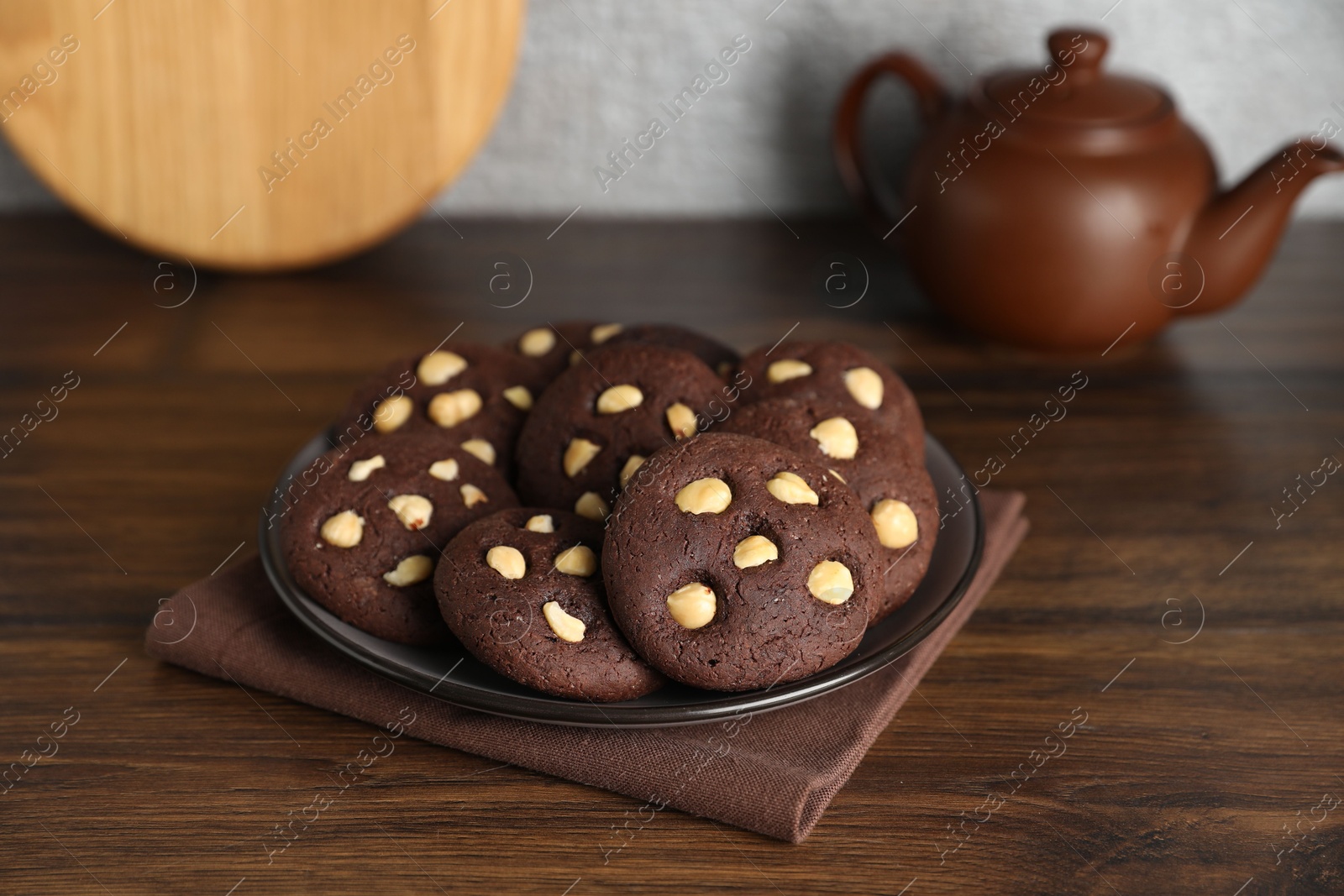 Photo of Tasty chocolate cookies with hazelnuts on wooden table, closeup