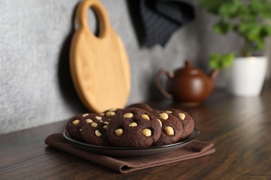 Photo of Tasty chocolate cookies with hazelnuts on wooden table