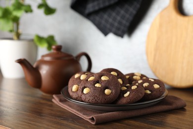 Photo of Tasty chocolate cookies with hazelnuts on wooden table, closeup