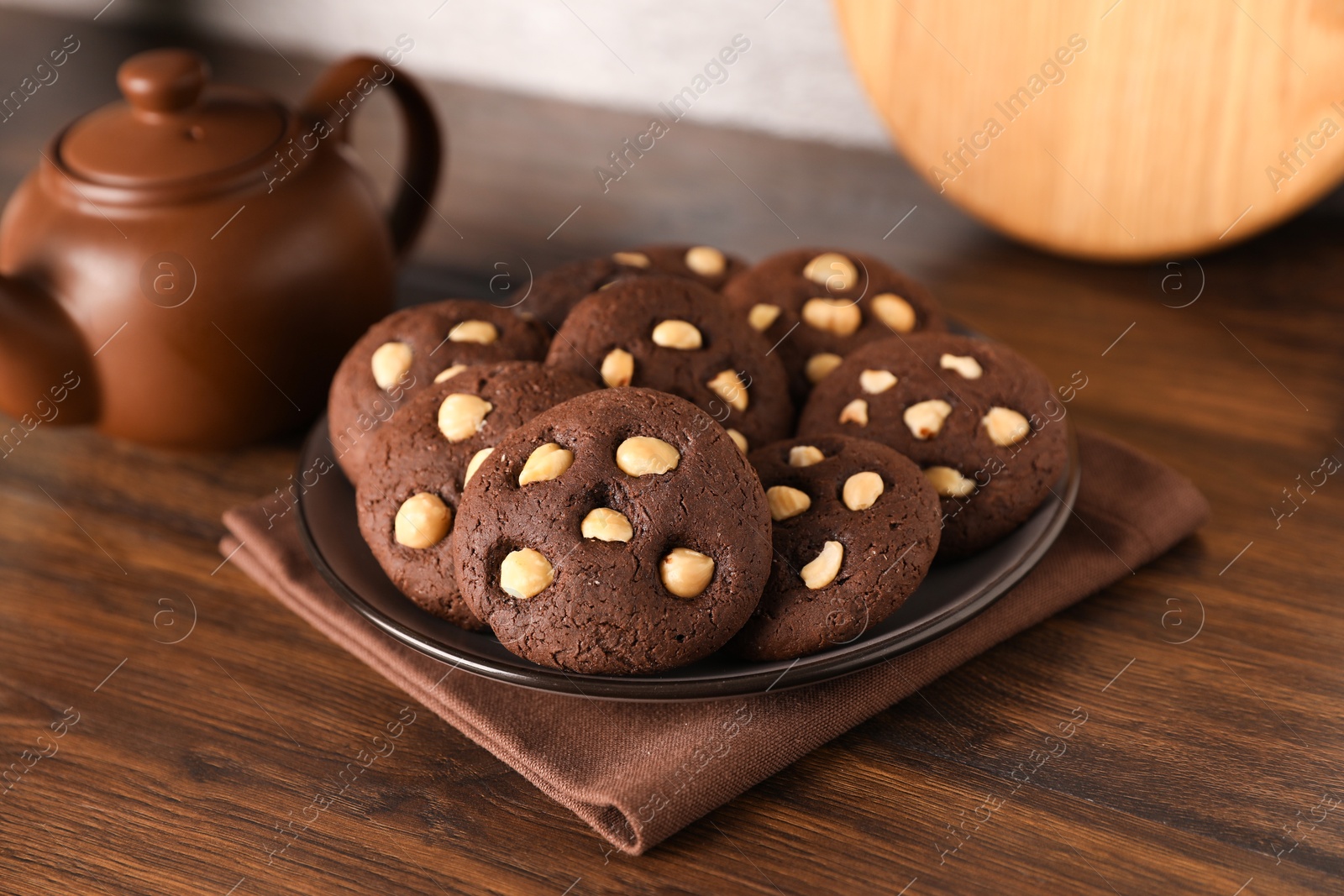 Photo of Tasty chocolate cookies with hazelnuts on wooden table, closeup