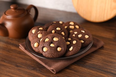 Photo of Tasty chocolate cookies with hazelnuts on wooden table, closeup