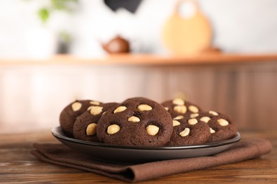 Photo of Tasty chocolate cookies with hazelnuts on wooden table, closeup