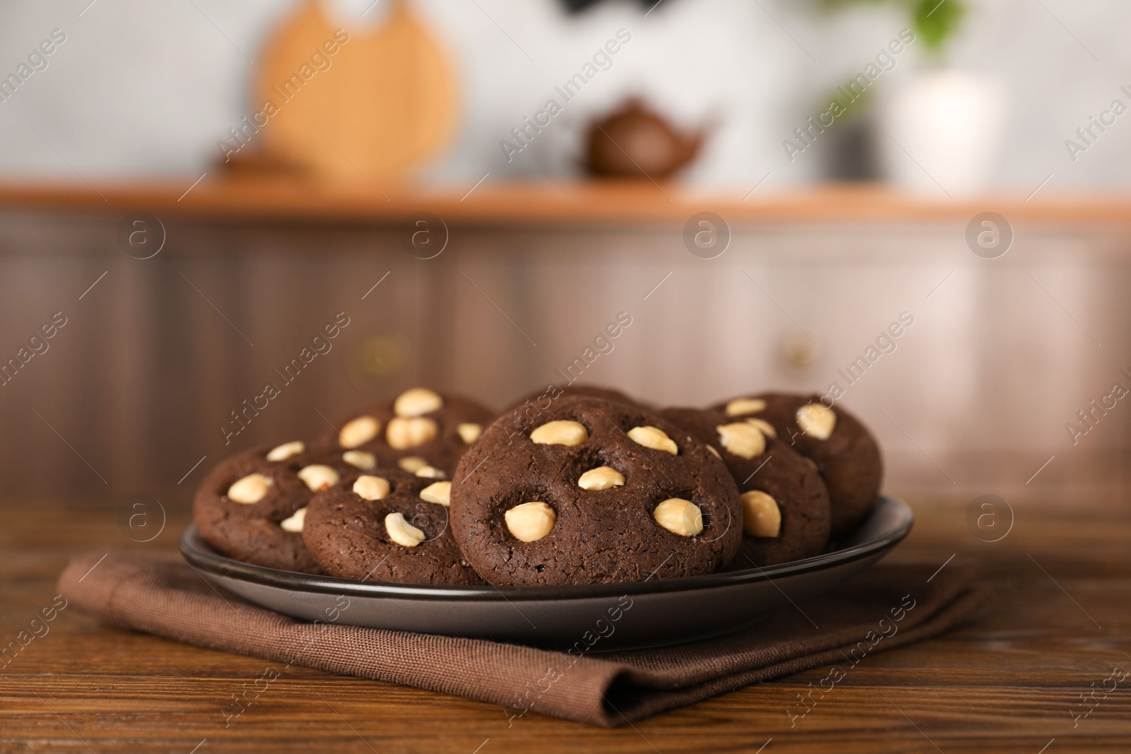 Photo of Tasty chocolate cookies with hazelnuts on wooden table, closeup