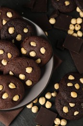 Photo of Tasty chocolate cookies with hazelnuts on black table, flat lay