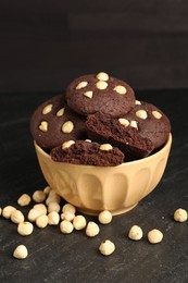 Photo of Tasty chocolate cookies with hazelnuts on black table