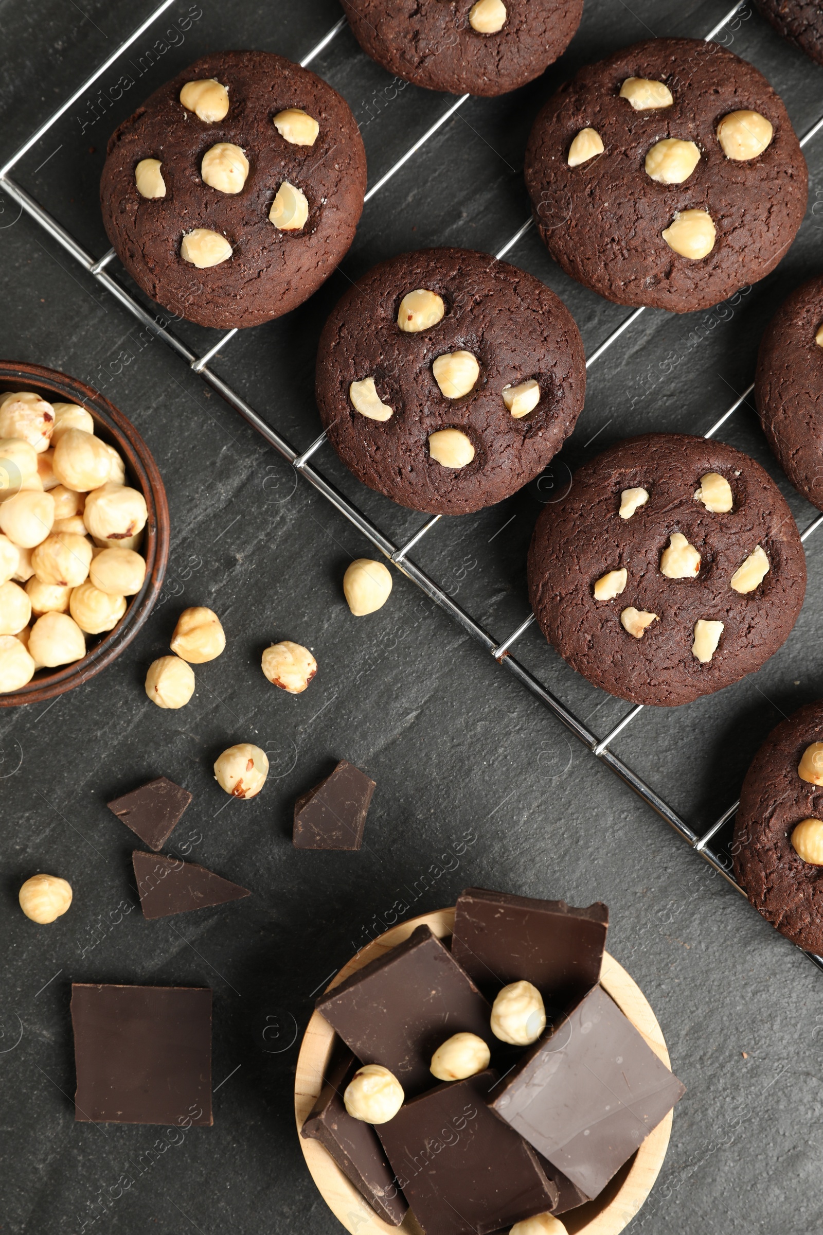 Photo of Tasty chocolate cookies with hazelnuts on black table, flat lay