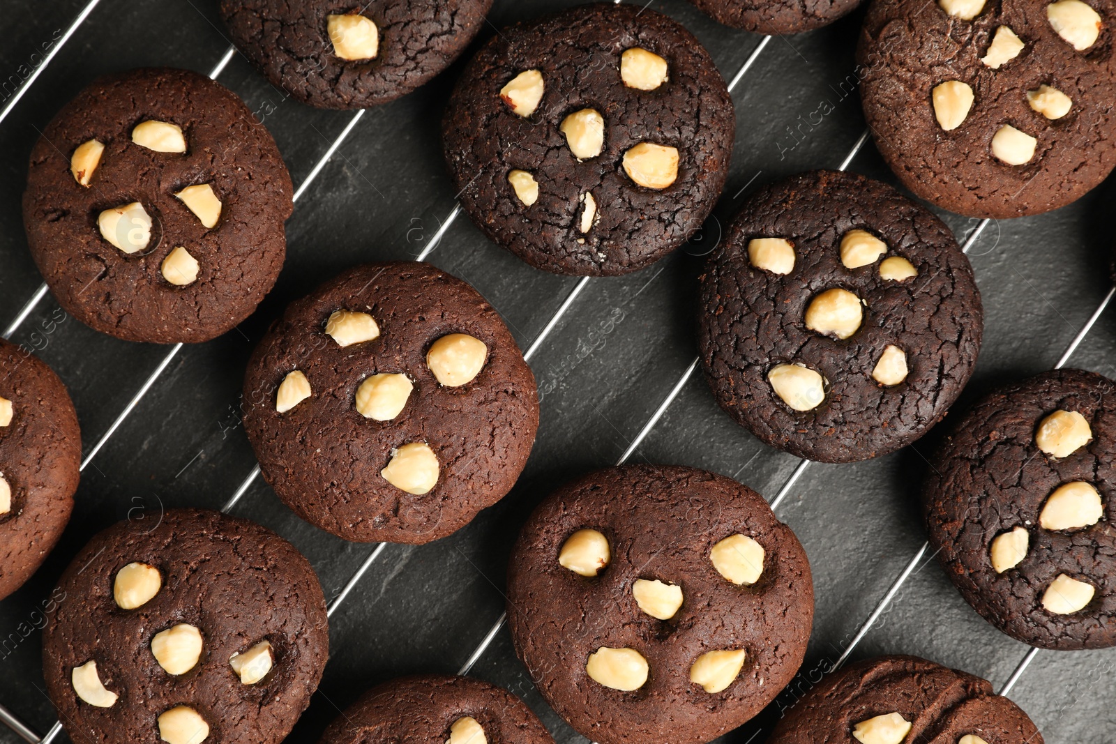 Photo of Tasty chocolate cookies with hazelnuts on black table, flat lay