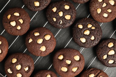 Photo of Tasty chocolate cookies with hazelnuts on black table, flat lay