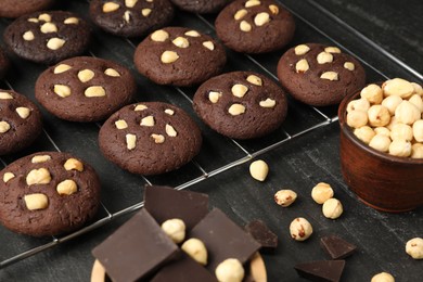 Photo of Tasty chocolate cookies with hazelnuts on black table, closeup