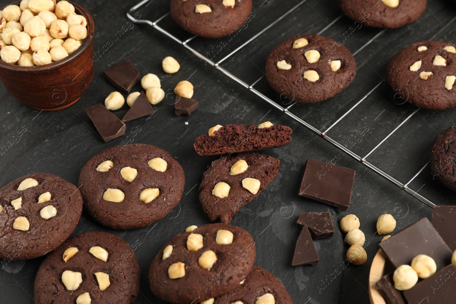 Photo of Tasty chocolate cookies with hazelnuts on black table, closeup