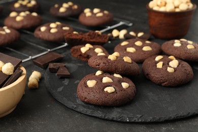 Photo of Tasty chocolate cookies with hazelnuts on black table, closeup