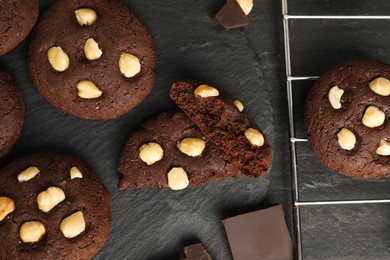 Photo of Tasty chocolate cookies with hazelnuts on black table, flat lay