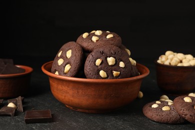 Photo of Tasty chocolate cookies with hazelnuts on black table, closeup