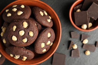 Photo of Tasty chocolate cookies with hazelnuts on black table, flat lay