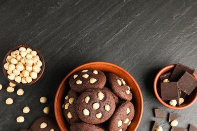 Photo of Tasty chocolate cookies with hazelnuts on black table, flat lay. Space for text