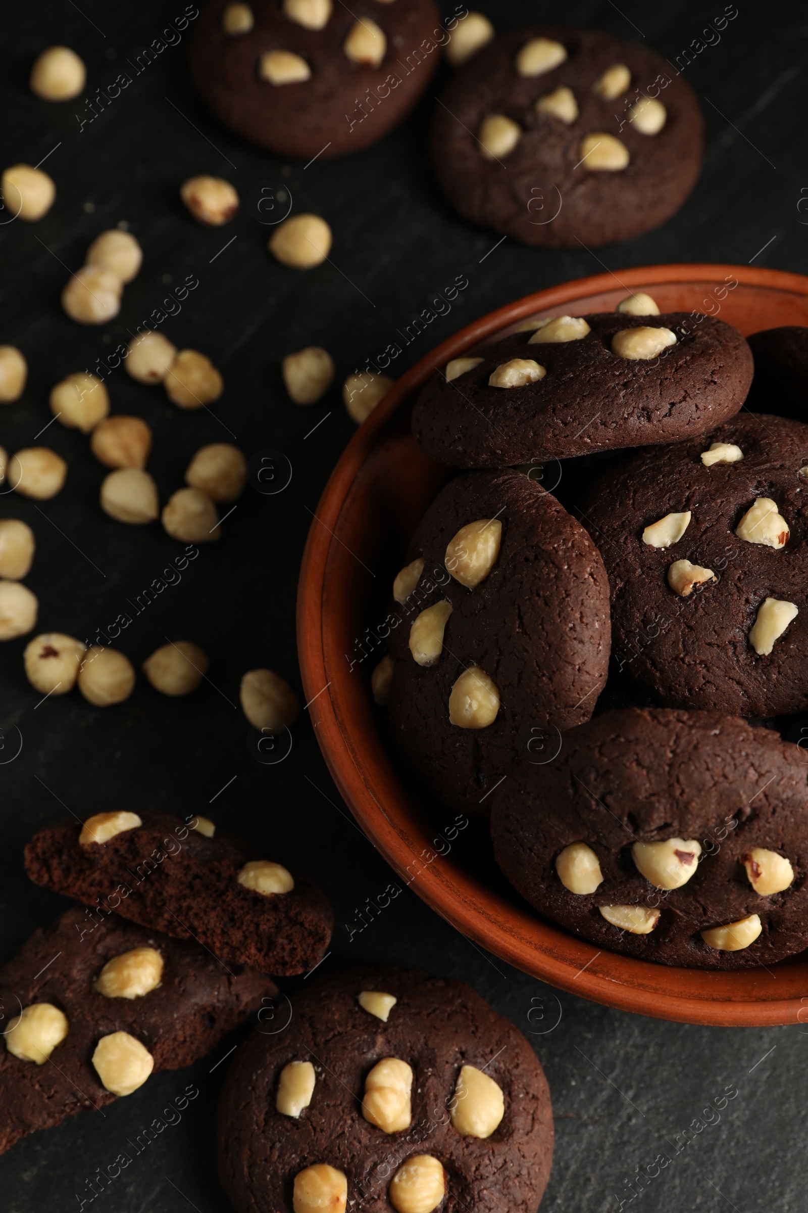 Photo of Tasty chocolate cookies with hazelnuts on black table, above view