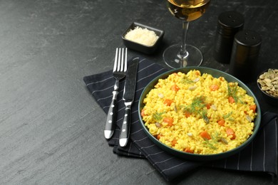 Photo of Delicious pumpkin risotto served on black table. Space for text