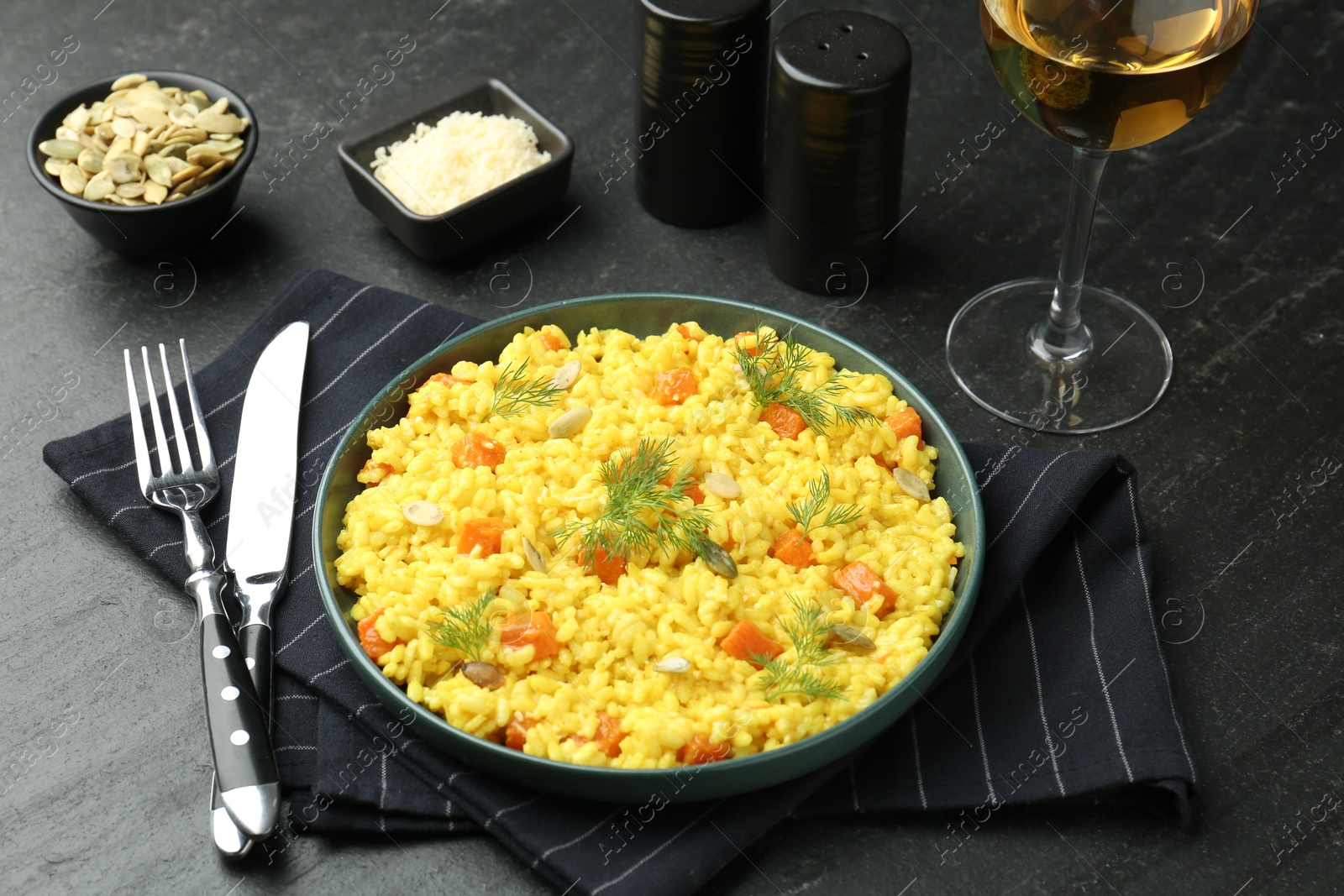 Photo of Delicious pumpkin risotto served on black table